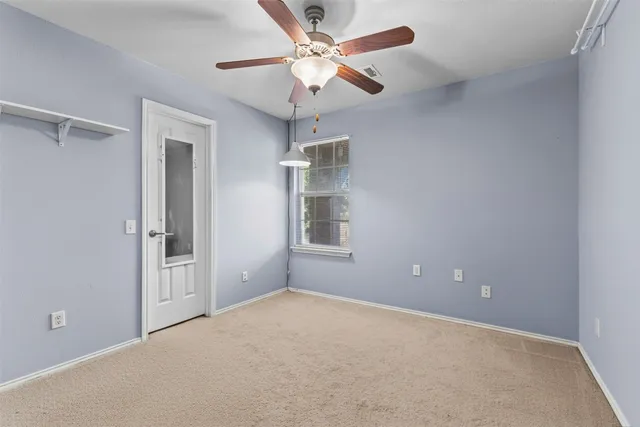 an empty room with windows and fan