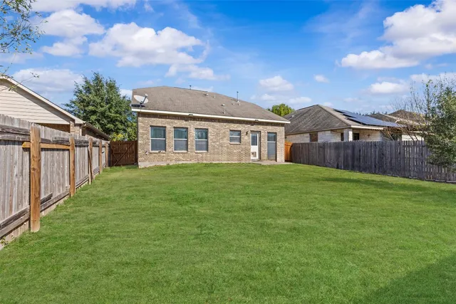 a view of a yard in front of a house with wooden fence