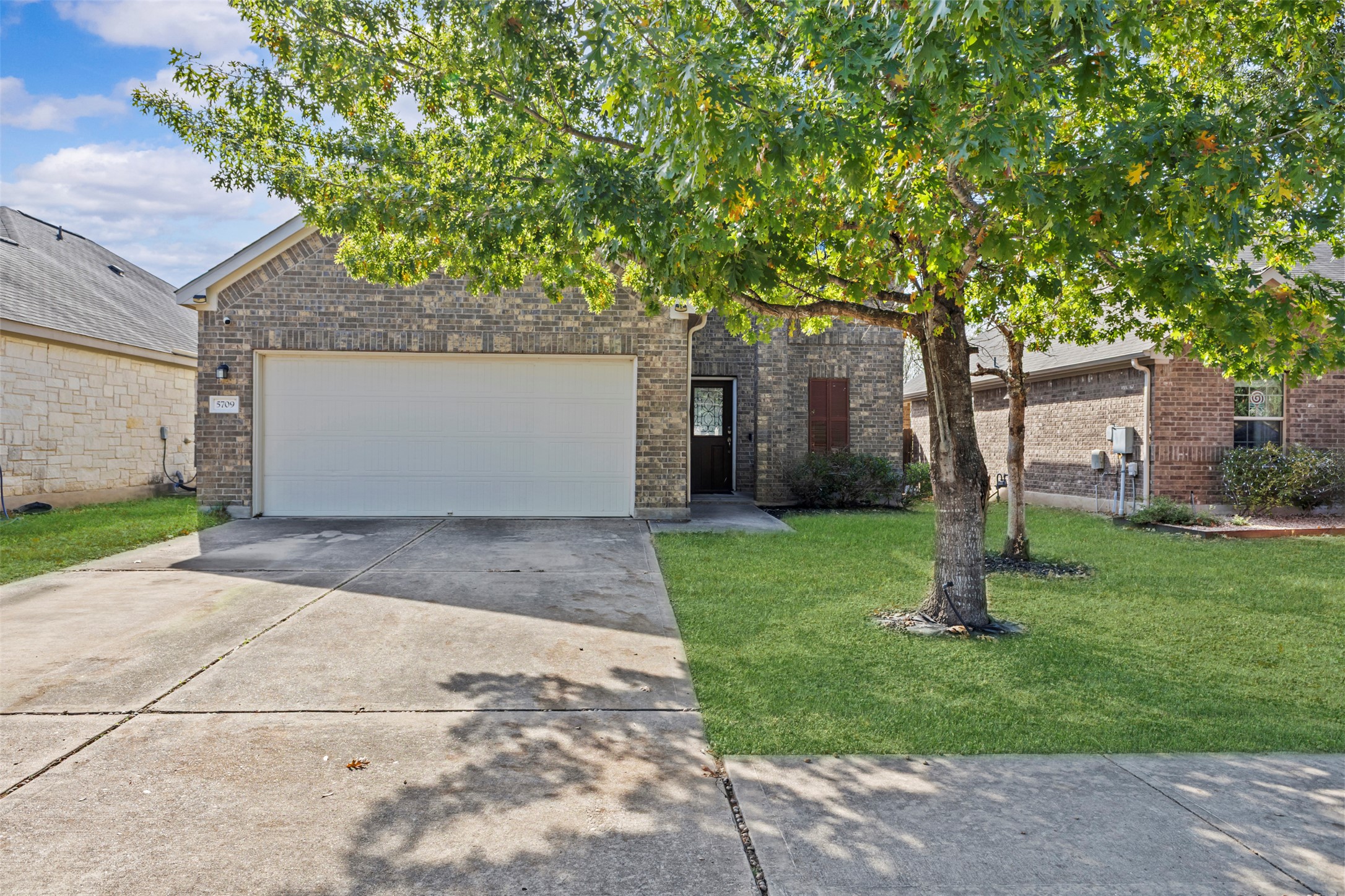 5709 Zachary Scott Street Austin, TX 78747 - Photo 4 of 29 a view of a white house next to a yard and a large tree