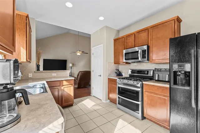 a kitchen with stainless steel appliances granite countertop a stove top oven a sink dishwasher a refrigerator and a stove with wooden floor