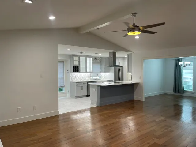 a large kitchen with a lot of counter space and wooden floor