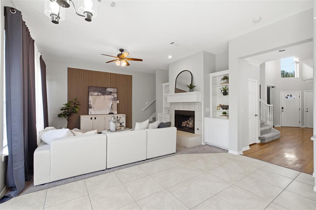 The expansive main level reveals just how much space this home delivers — family room, built-ins, fireplace, and the gracious foyer with its grand staircase all visible in one sweeping view. Tile flooring transitions to rich hardwood as the rooms connect seamlessly from front to back.
