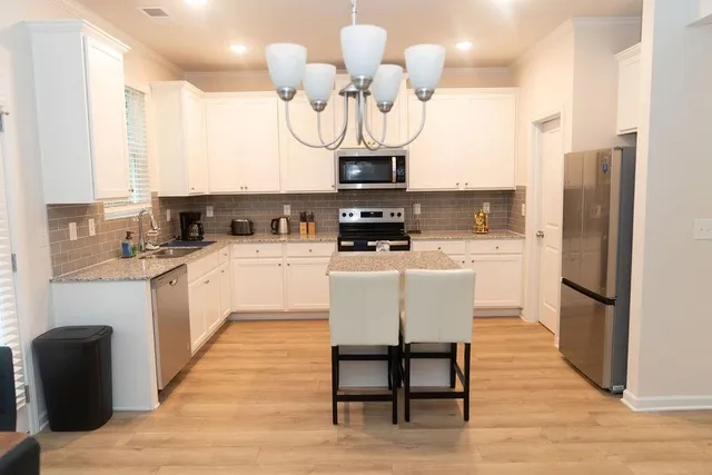 a kitchen with stainless steel appliances a refrigerator a stove a sink dishwasher with a dining table and chairs