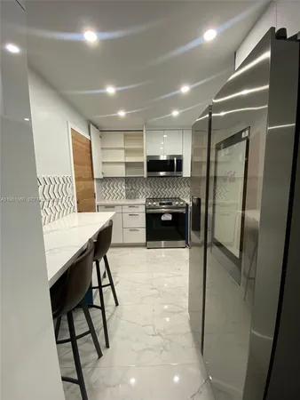 a kitchen with kitchen island a counter top space a refrigerator a stove a microwave and cabinets