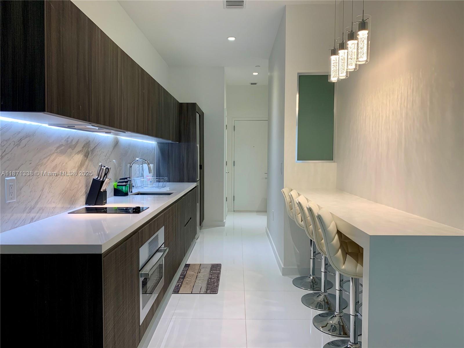 851 Northeast 1st Avenue, Unit 502 Miami, FL 33132 - Photo 4 of 48 a kitchen with granite countertop a sink and stove