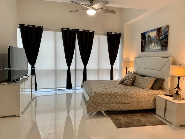 a bedroom with a bed a flat screen tv and dresser