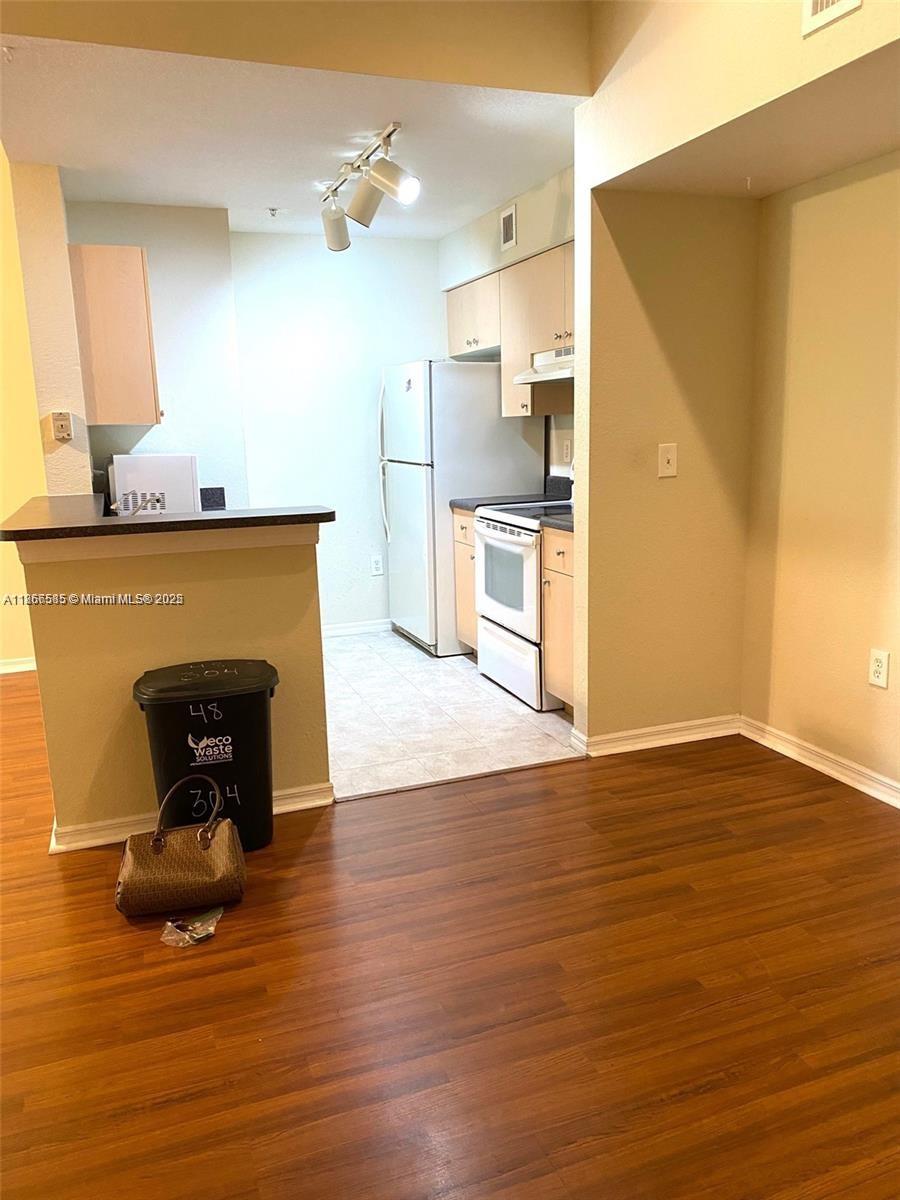2564 Centergate Drive, Unit 304 Miramar, FL 33025 - Photo 12 of 13 a kitchen with stainless steel appliances wooden floor and a refrigerator