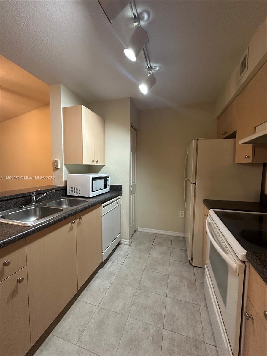2564 Centergate Drive, Unit 304 Miramar, FL 33025 - Photo 3 of 13 a kitchen with granite countertop a sink and white cabinets