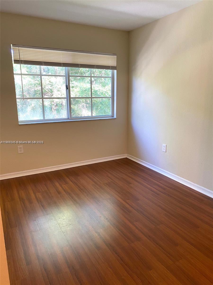 2564 Centergate Drive, Unit 304 Miramar, FL 33025 - Photo 6 of 13 a view of an empty room with wooden floor and a window