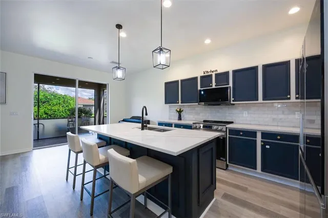 a kitchen with stainless steel appliances granite countertop a stove a sink a microwave a center island and a refrigerator