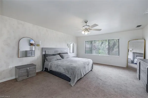 a spacious bedroom with a bed a couch and large window