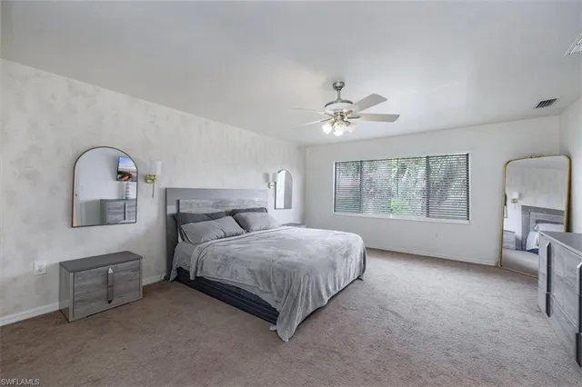 a spacious bedroom with a bed a couch and large window