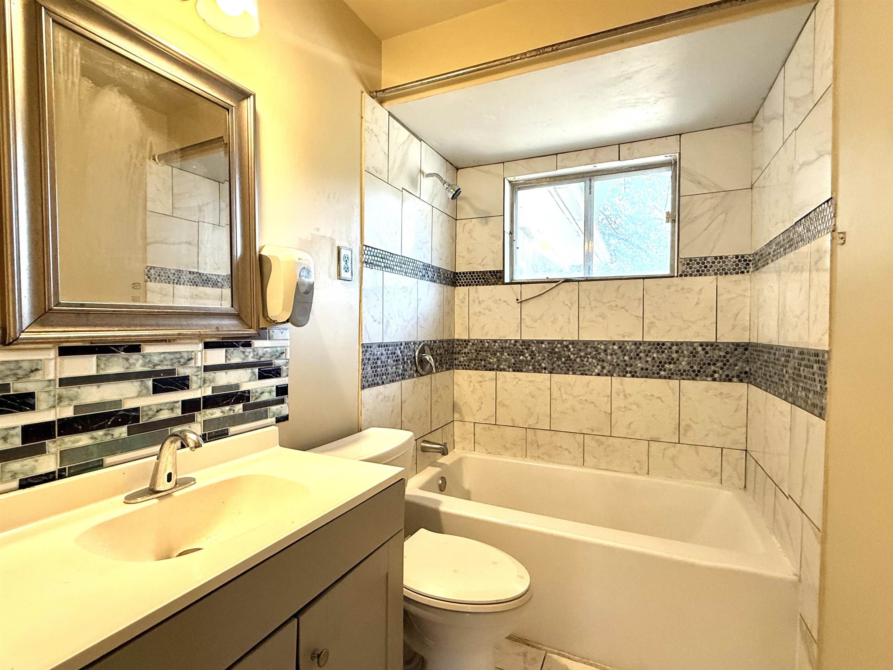 2930 Getwell Road Memphis, TN 38118 - Photo 14 of 25 Bathroom featuring a combination bathtub and shower with white tile surround and decorative mosaic accents