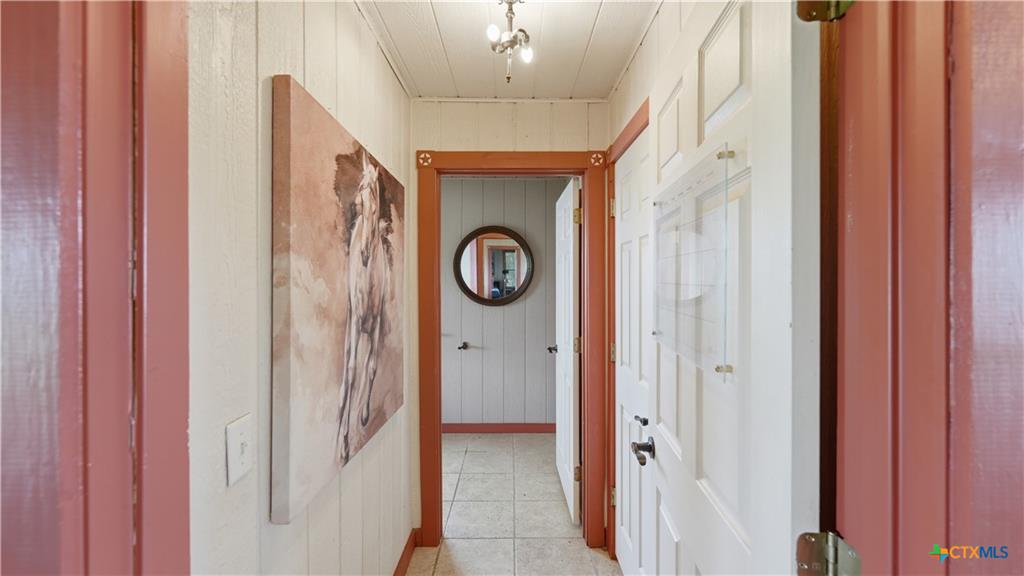 127 Offer Llano, TX 78643 - Photo 18 of 40 Hallway featuring vertical wood paneling, tile flooring, and wood door frames