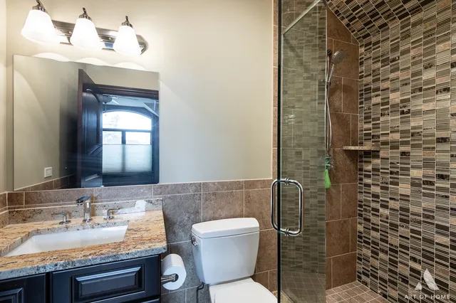 a bathroom with a granite countertop toilet sink and mirror