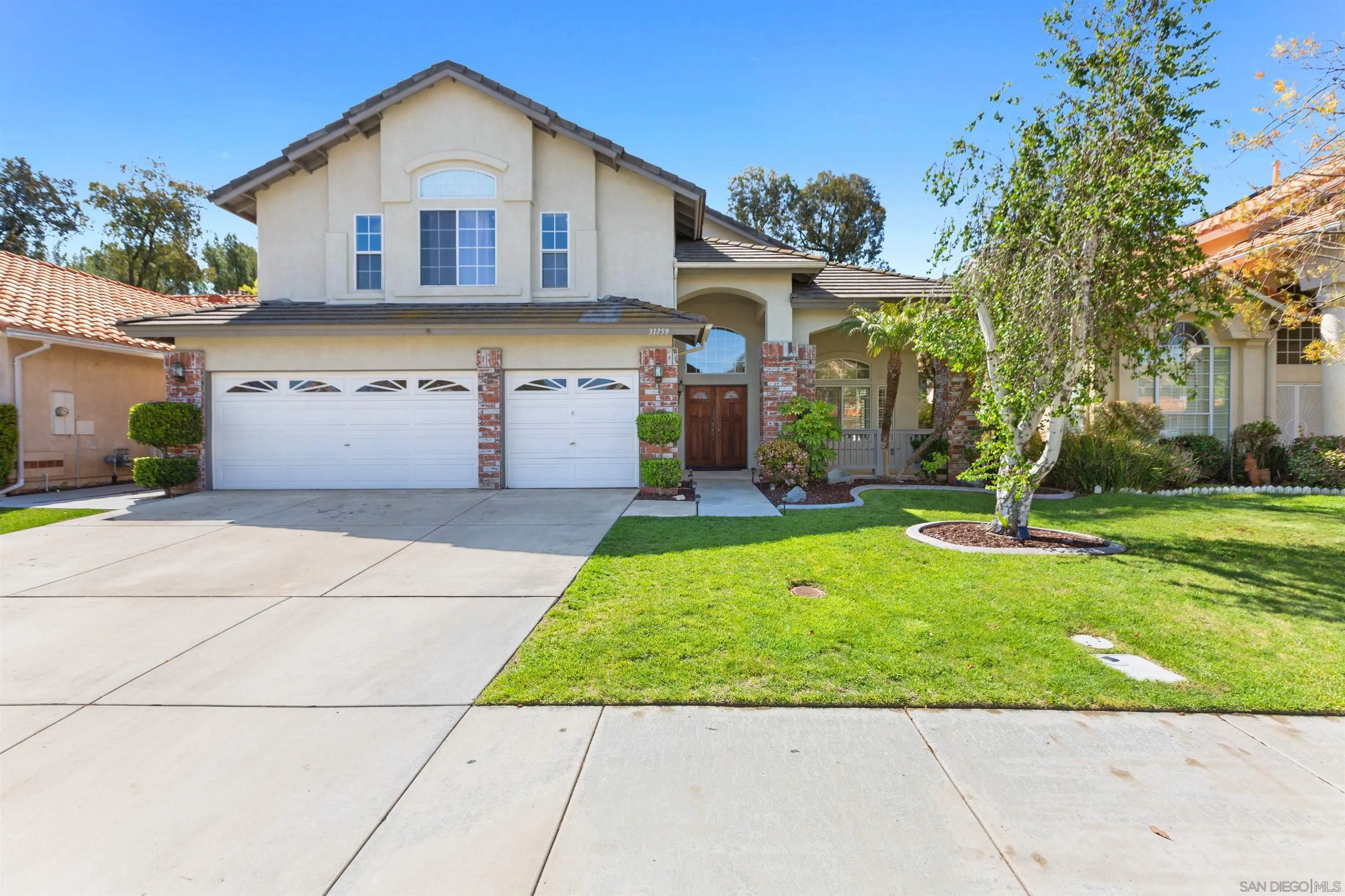 a view of a white house next to a yard with big trees