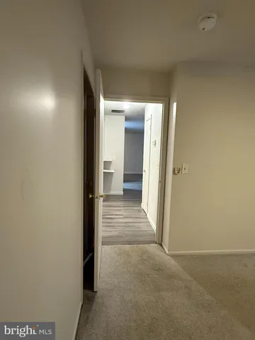 a view of a hallway with wooden floor and a bathroom