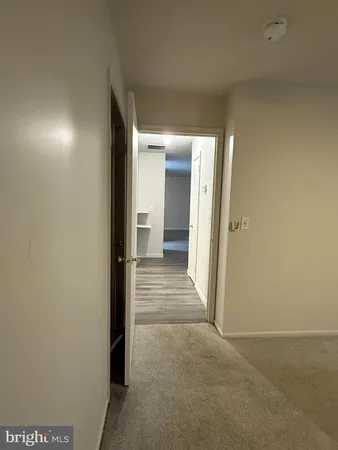 a view of a hallway with wooden floor and a bathroom