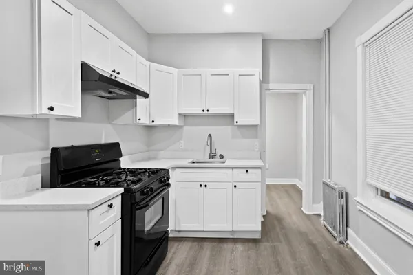 a kitchen with stainless steel appliances a stove a sink and white cabinets