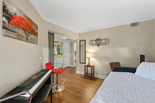 a bedroom with a bed and a dresser with wooden floor