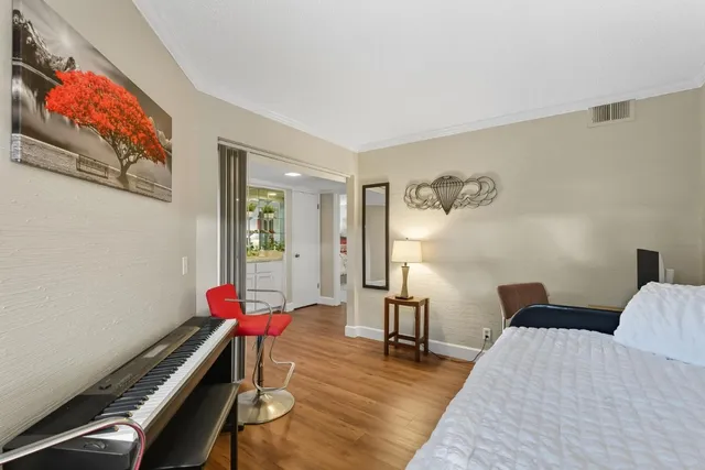 a bedroom with a bed and a dresser with wooden floor