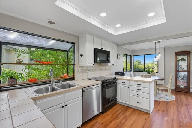 a kitchen with stainless steel appliances white cabinets large window and wooden floor