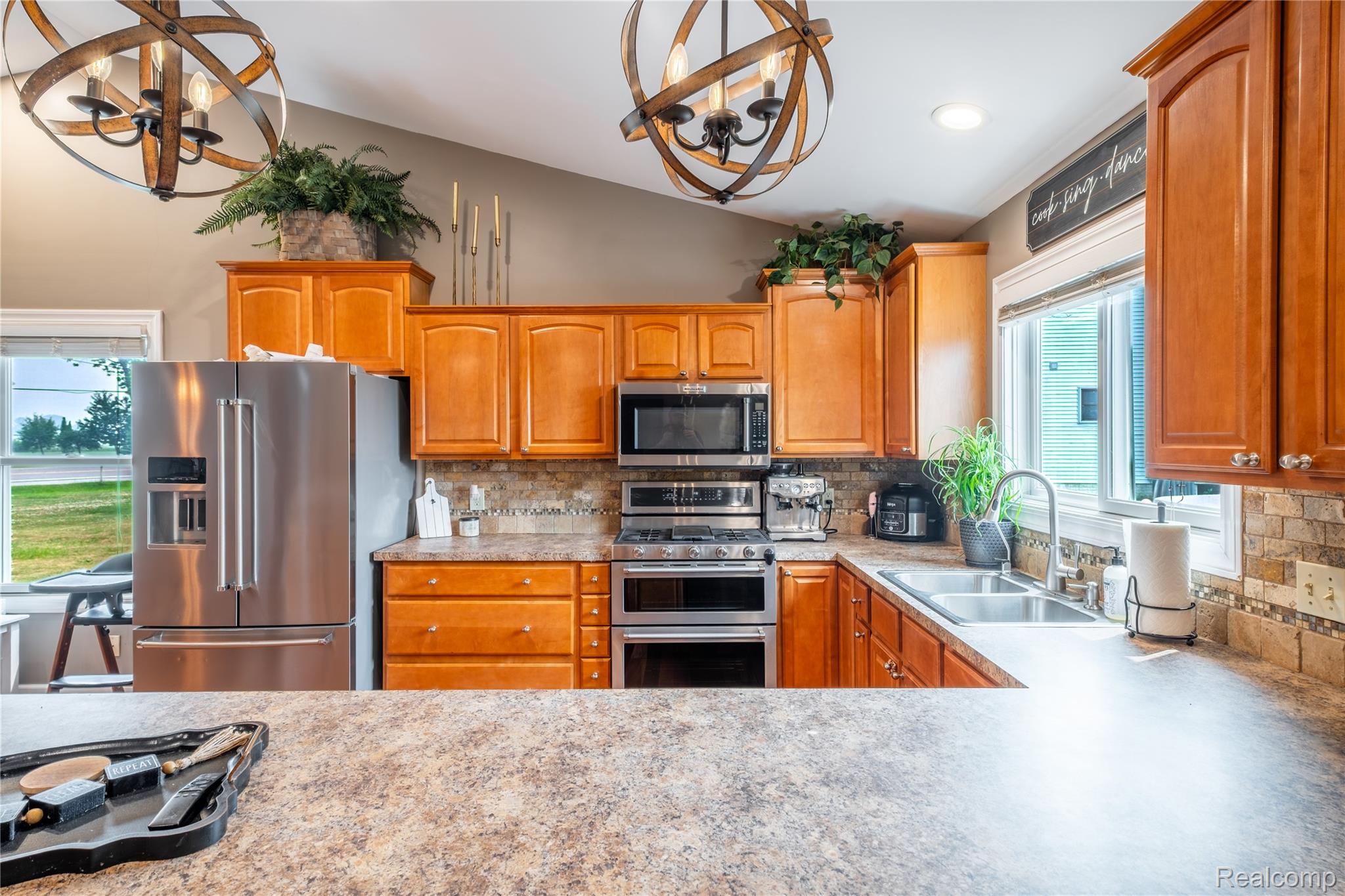 10250 Duffield Road Gaines, MI 48436 - Photo 21 of 28 Kitchen featuring wood cabinetry, stainless steel appliances, stone-look countertops, and a tile backsplash