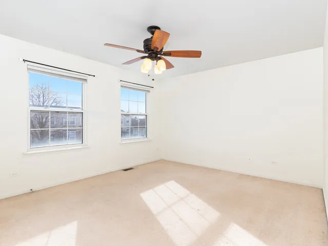 an empty room with chandelier fan and windows