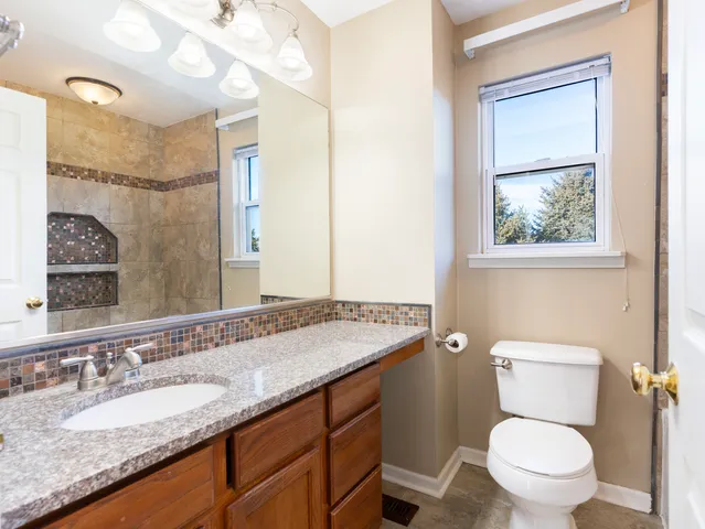 a bathroom with a granite countertop toilet a sink and a mirror