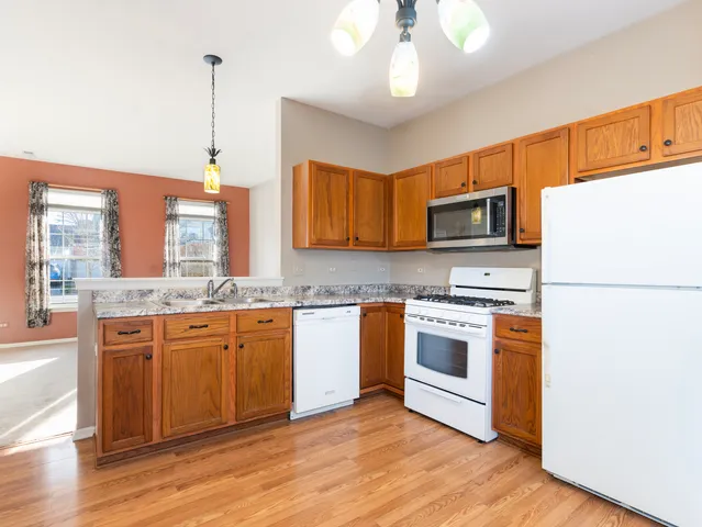 a kitchen with stainless steel appliances granite countertop a refrigerator a stove top oven a sink and dishwasher with wooden floor