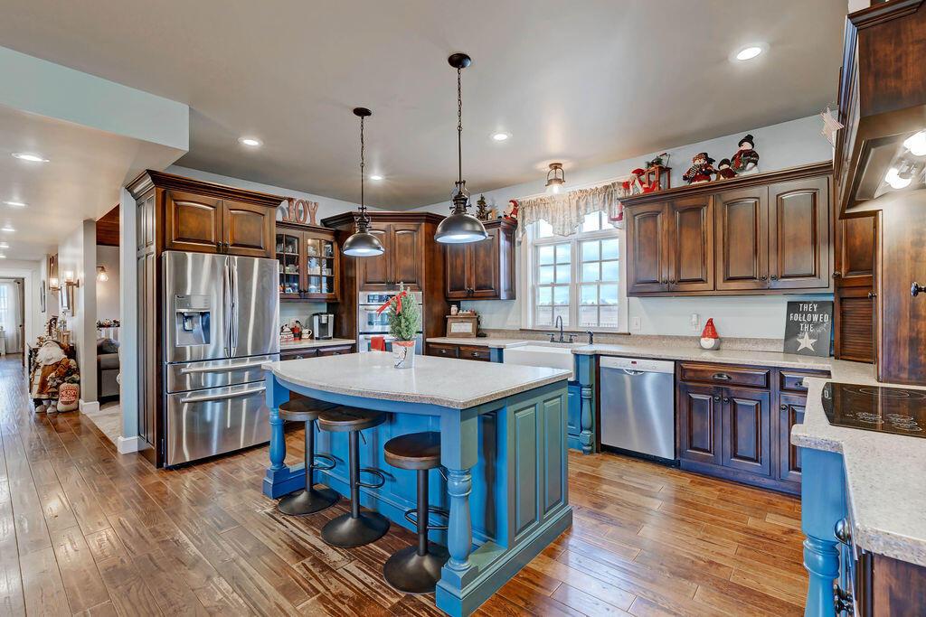 4045 Russell Road Mount Gilead, OH 43338 - Photo 16 of 74 • Handscraped hardwood flooring • Baby blue painted walls • Amish custom cabinets • New KitchenAid® stainless steel refrigerator ~ 2019 • New KitchenAid® stainless steel dishwasher ~ 2019 • KitchenAid® stainless steel convection oven/microwave oven bottom • Farmhouse sink • Pantry • Electric stovetop with hood • Large island with seating • Corian® countertops