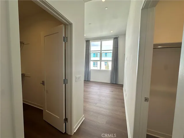 a view of a hallway with wooden floor and a room