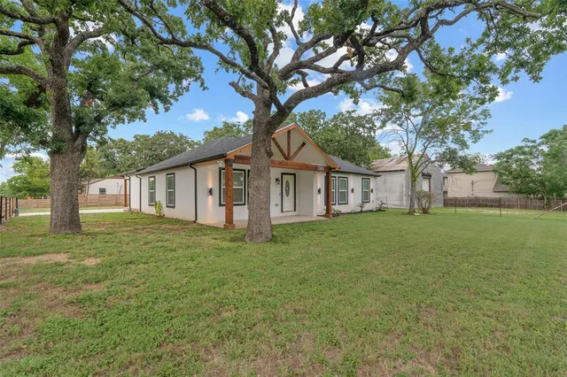 a view of a yard in front of a house with large tree