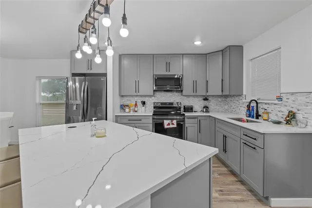 a kitchen with kitchen island granite countertop stainless steel appliances cabinets a sink and a counter top