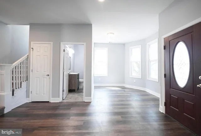 an empty room with wooden floor mirror and windows