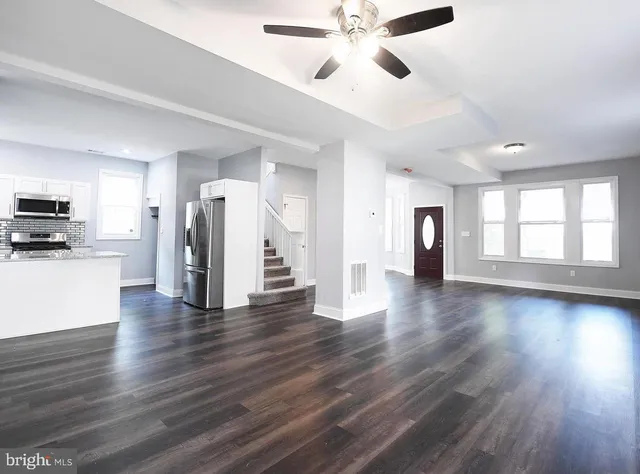 a view of an empty room with a window and wooden floor