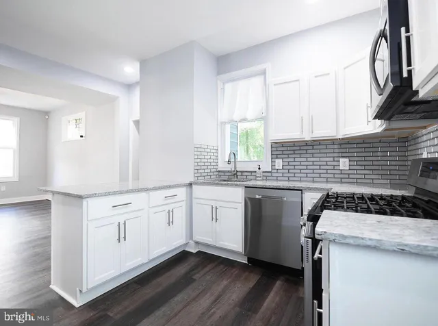 a kitchen with granite countertop a sink a stove and cabinets