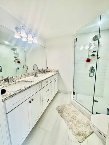 a bathroom with a granite countertop sink a mirror and shower