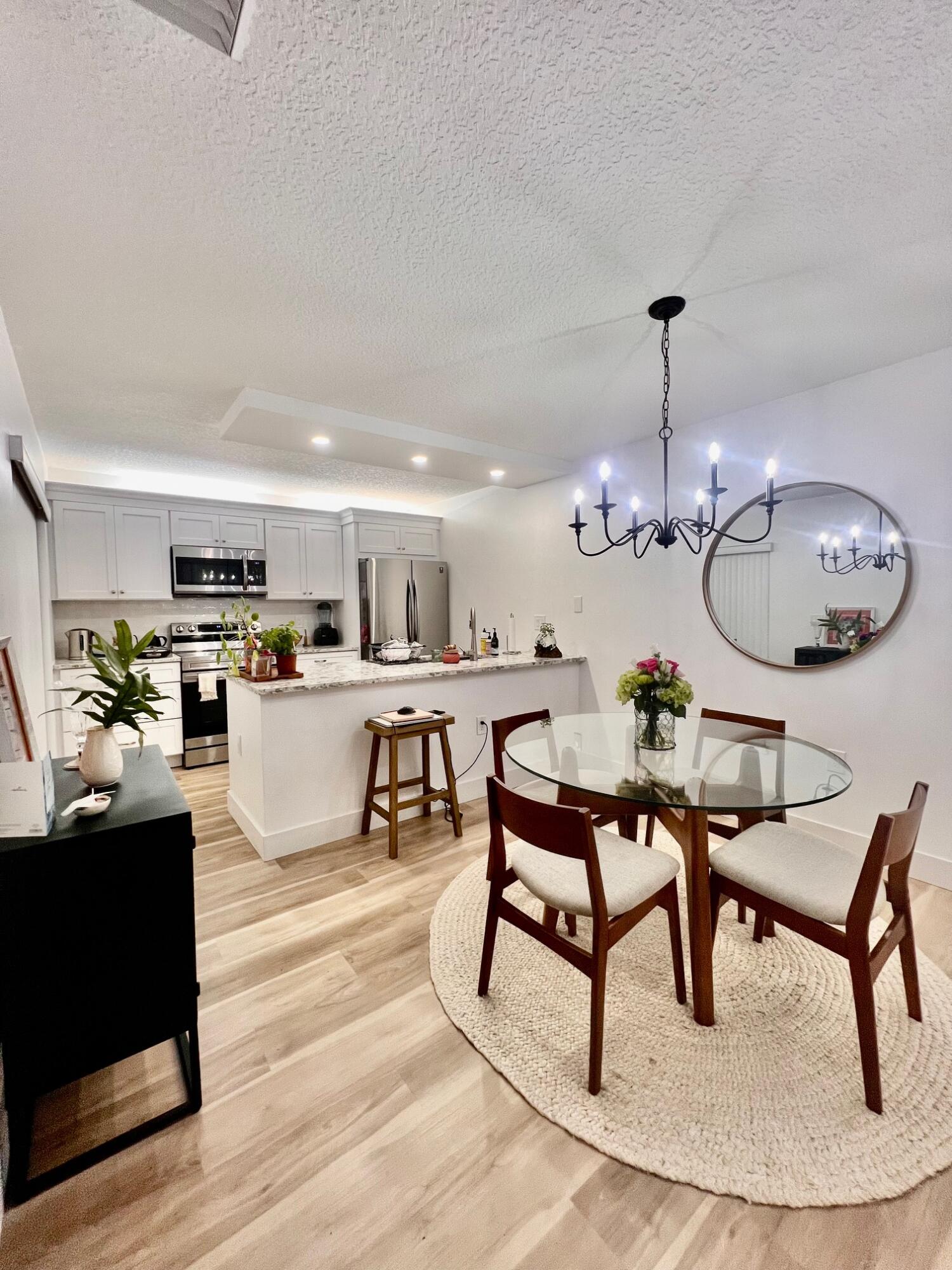 3105 31st Court, Unit 130D Jupiter, FL 33477 - Photo 6 of 24 a living room with furniture kitchen view and a chandelier