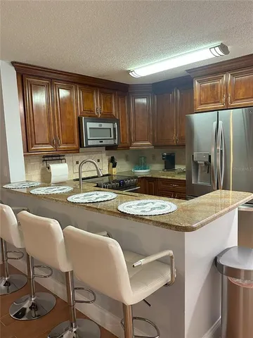 a kitchen with stainless steel appliances granite countertop a refrigerator a stove a sink and chairs