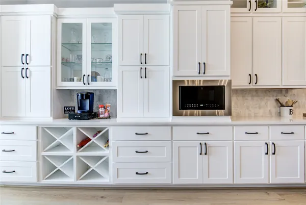 a kitchen with white cabinets and window