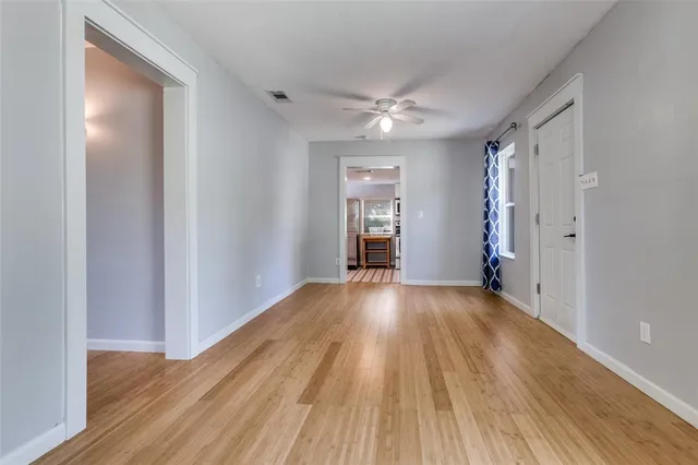 a view of empty room with wooden floor and fan