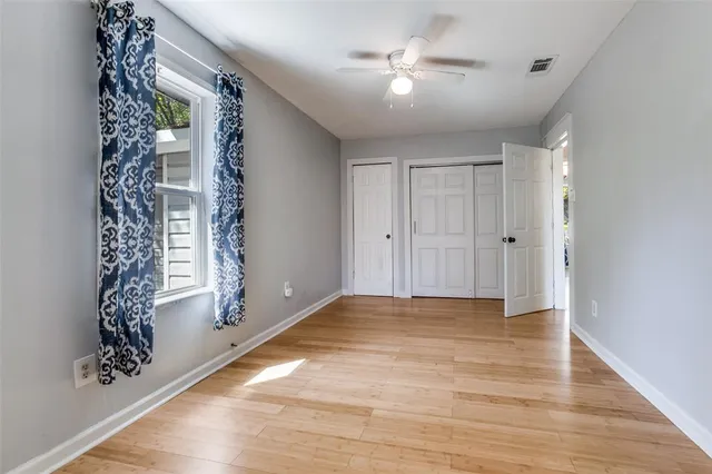 a view of an empty room with chandelier fan and wooden floor