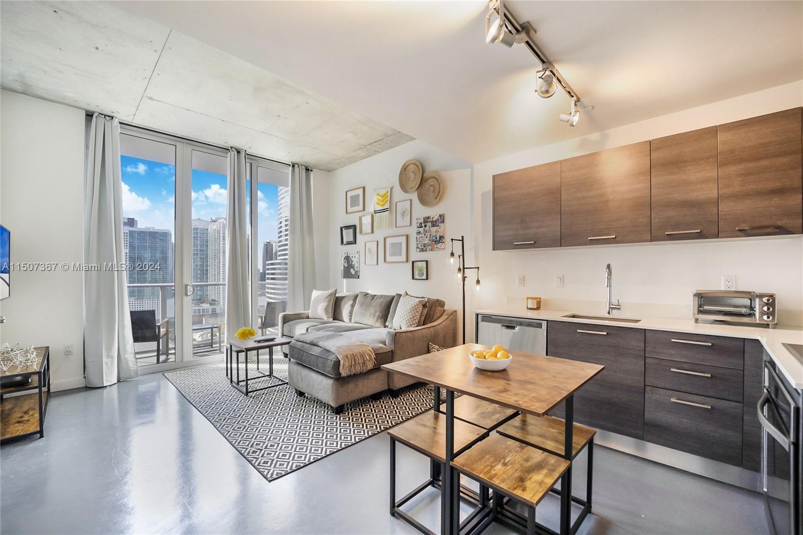 a living room with furniture a rug kitchen view and a large window