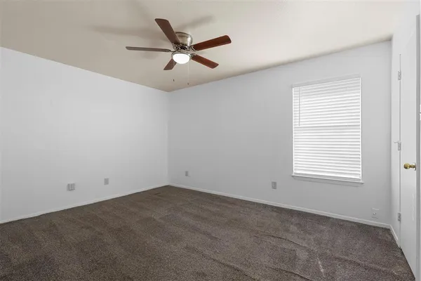 an empty room with a window and a fan
