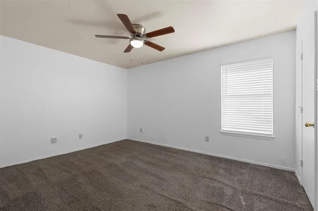 an empty room with a window and a fan