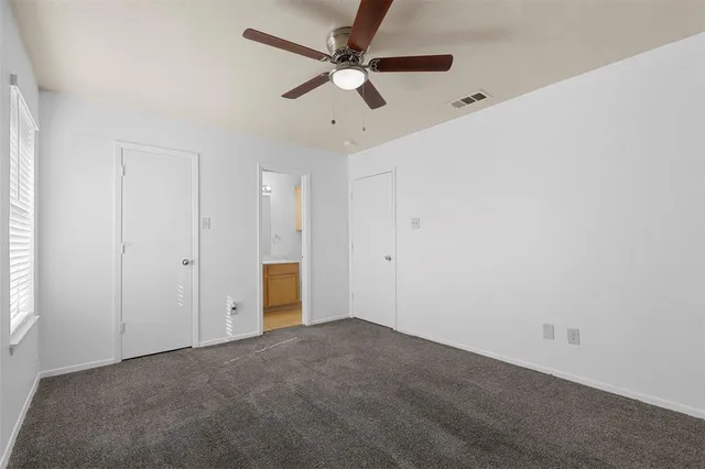 an empty room with a ceiling fan and a window