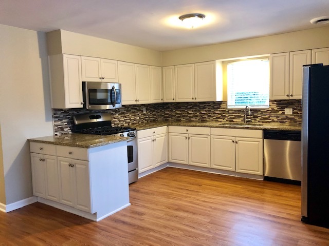 40 Valley Road Glen Ellyn, IL 60137 - Photo 15 of 24 a kitchen with stainless steel appliances white cabinets a sink a stove a microwave and wooden floor
