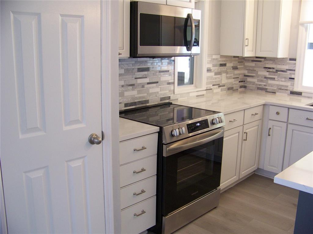 15550 Burnt Store Road, Unit 202 Punta Gorda, FL 33955 - Photo 13 of 61 a kitchen with granite countertop white cabinets and stainless steel appliances