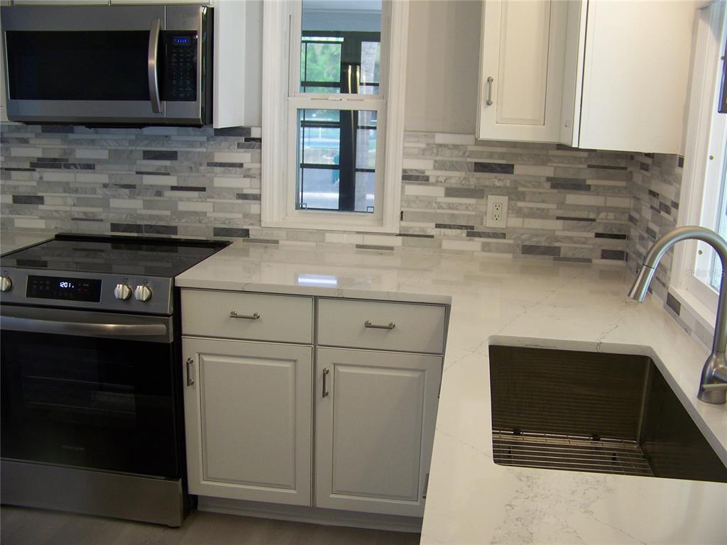 15550 Burnt Store Road, Unit 202 Punta Gorda, FL 33955 - Photo 14 of 61 a kitchen with stainless steel appliances a stove microwave and sink